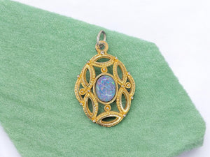 gold color metal pendant with faux opal in middle