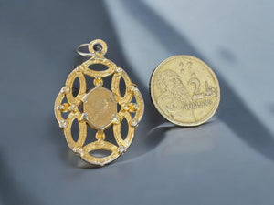 gold color metal pendant with faux opal in middle